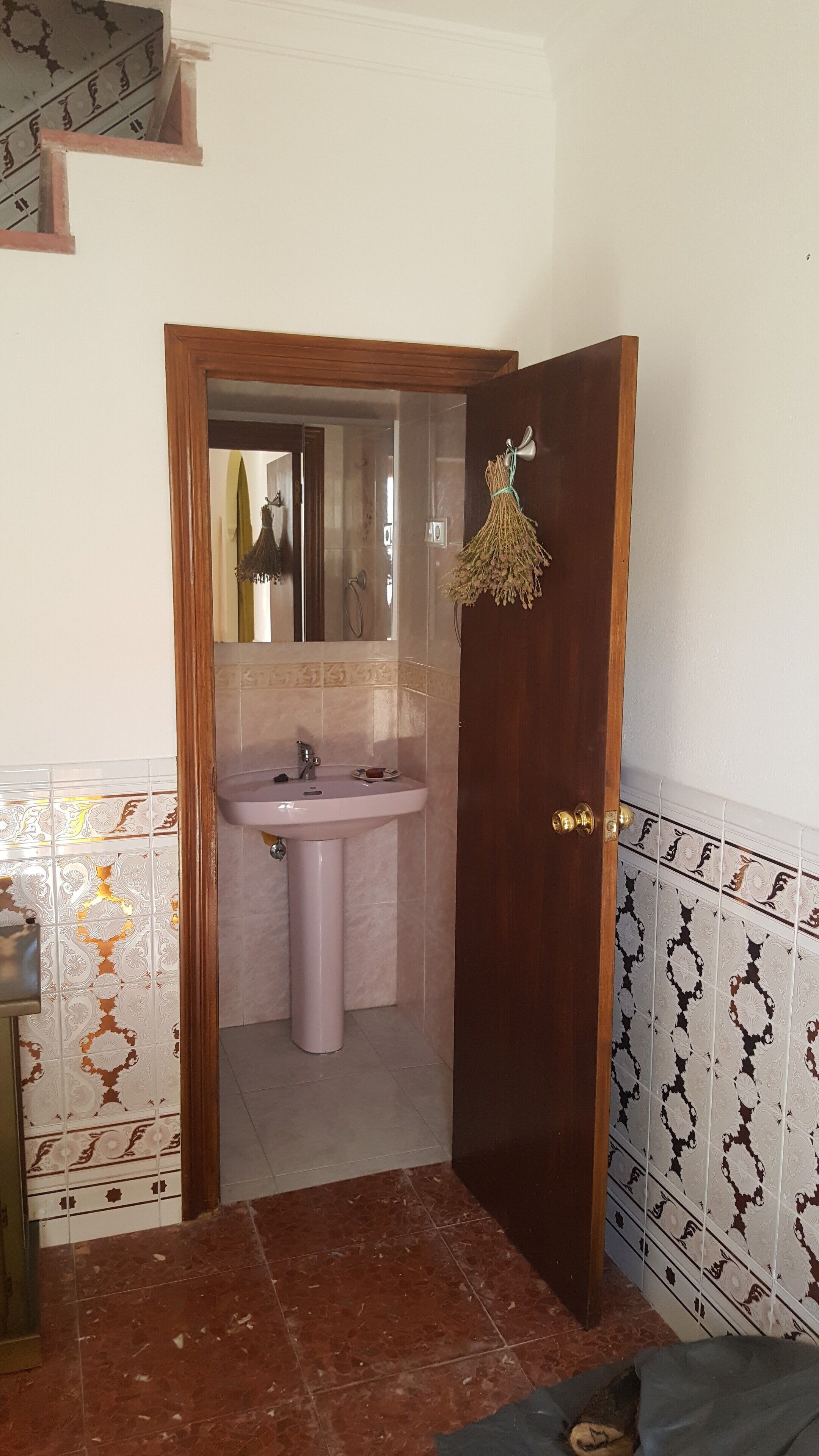 Un baño con lavabo, espejo y una puerta con fleco decorativo.