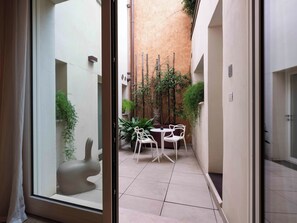 A narrow outdoor corridor with a tiled floor, white chairs, and potted plants. - Leoni di Collalto Palace (Treviso)