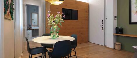 Un comedor moderno con una mesa redonda, sillas negras, un jarrón original con flores e iluminación colgante.