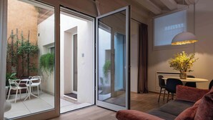 A modern interior with a sliding glass door leading to a balcony, a sofa, a table with chairs, and a decorative vase with flowers. - Leoni di Collalto Palace (Treviso)