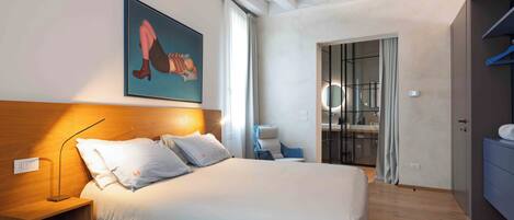 A bedroom with a bed, bedside table, and a painting on the wall.