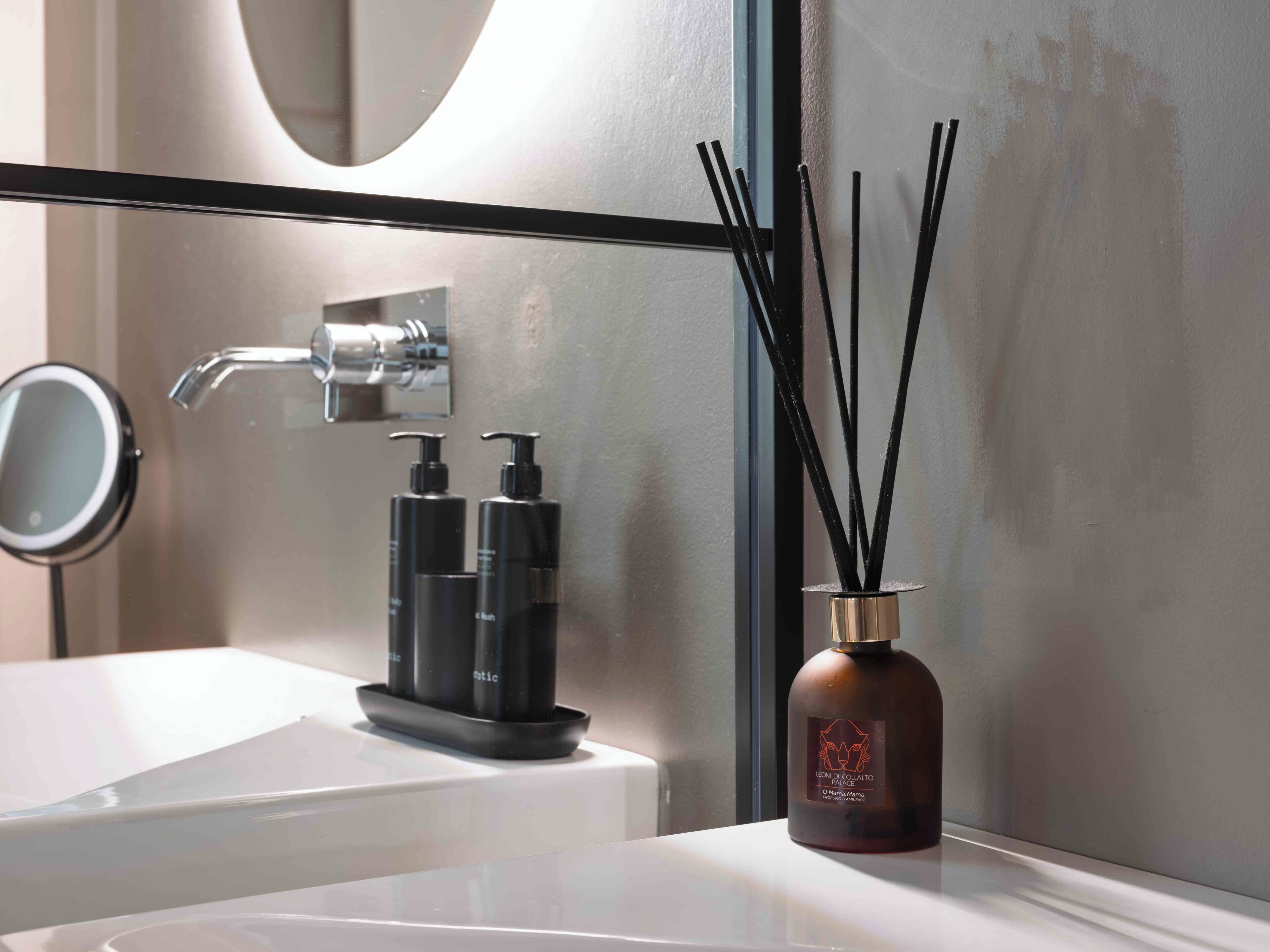 Ein Badezimmer mit Spiegel, Wasserhahn und einer Flasche mit Schilferdiffusor.
