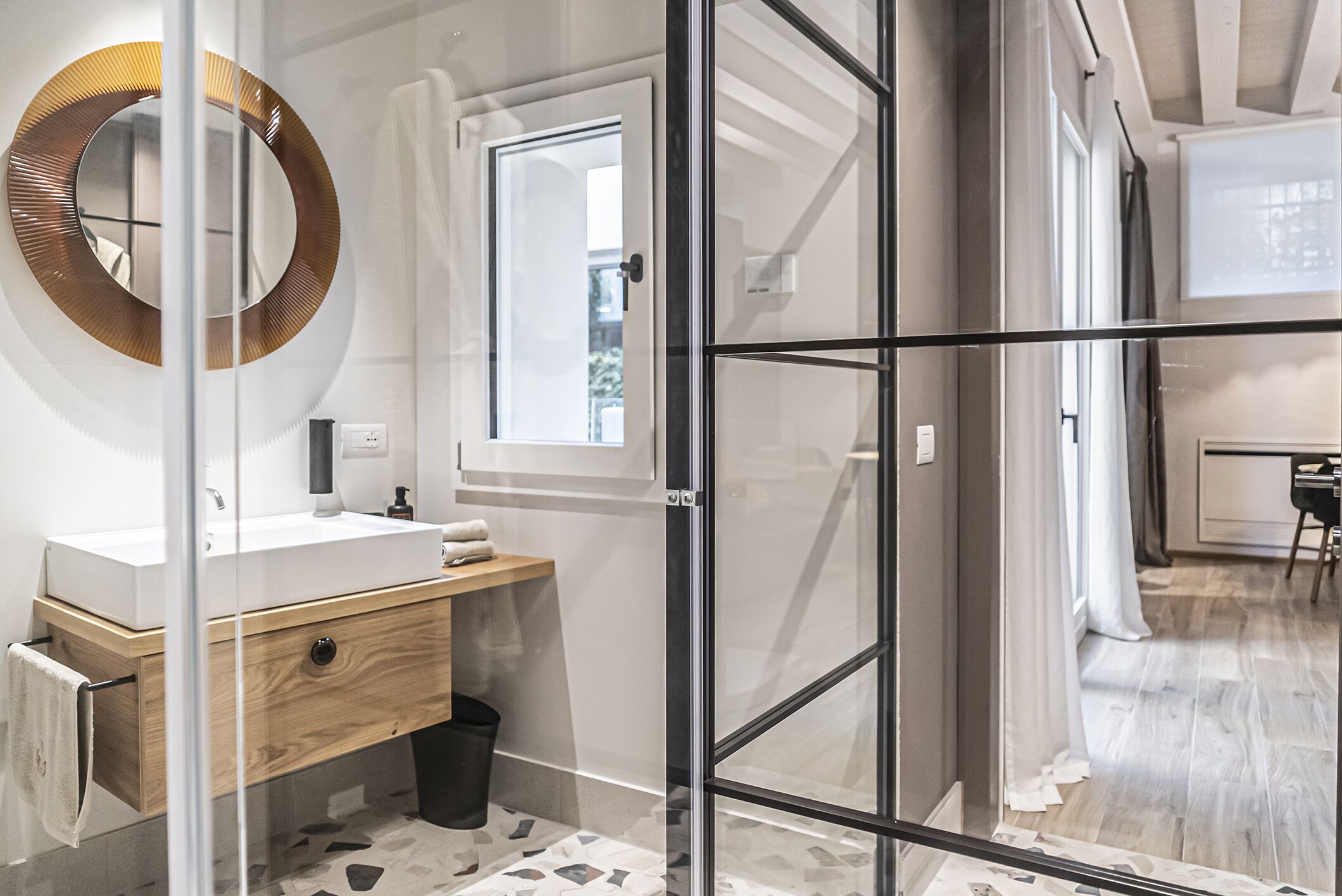 A modern bathroom with a glass-enclosed shower, a wooden vanity, and a large mirror.