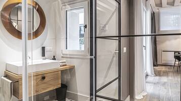 A modern bathroom with a glass-enclosed shower, a wooden vanity, and a large mirror.