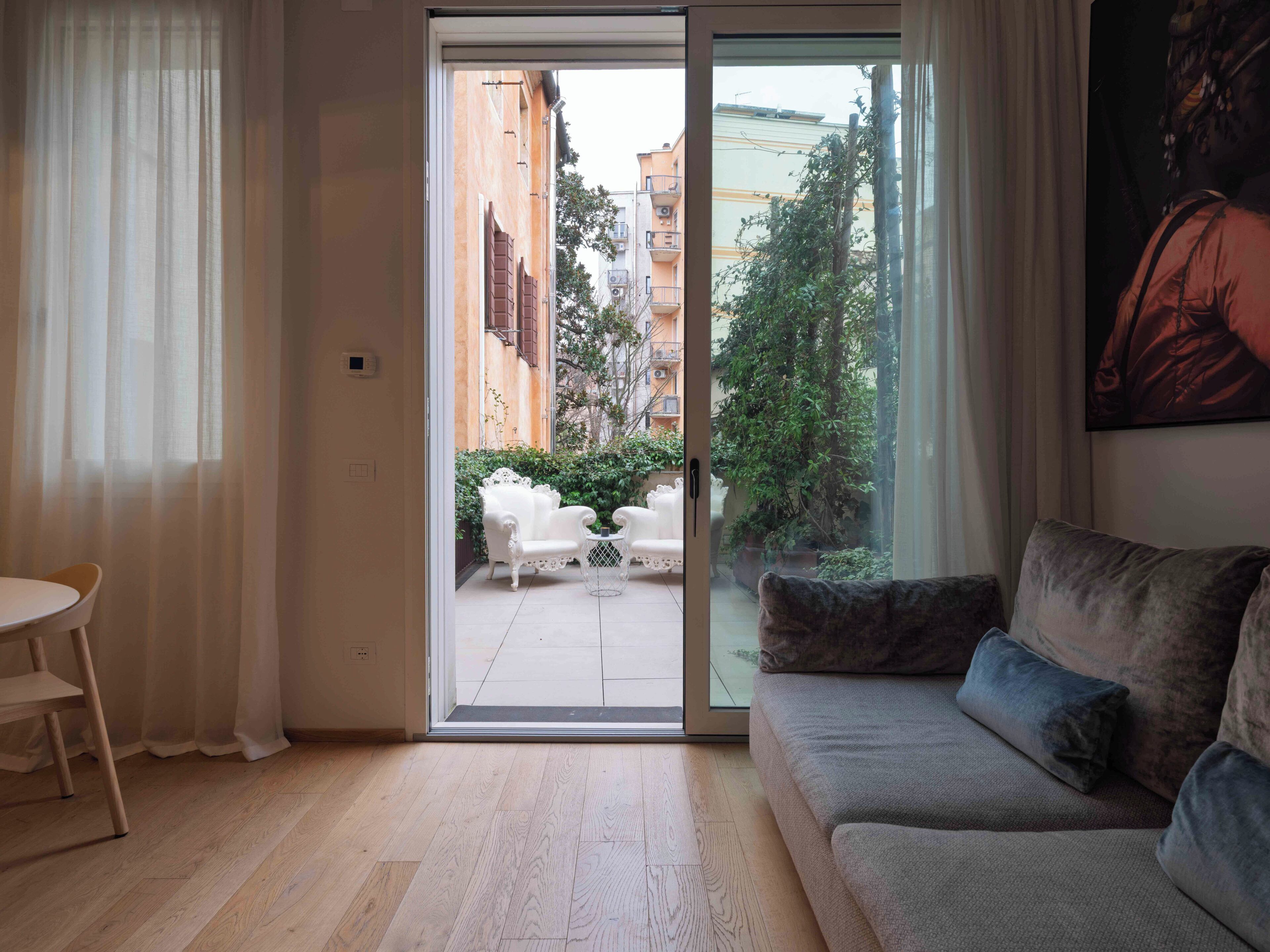 A living room with a sliding glass door leading to a balcony, a sofa, a chair, and a small table.