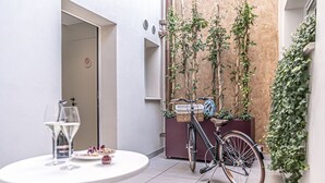 A narrow outdoor space with a bicycle, a table with a glass of wine, and a door with a no-smoking sign. - Leoni di Collalto Palace (Treviso)