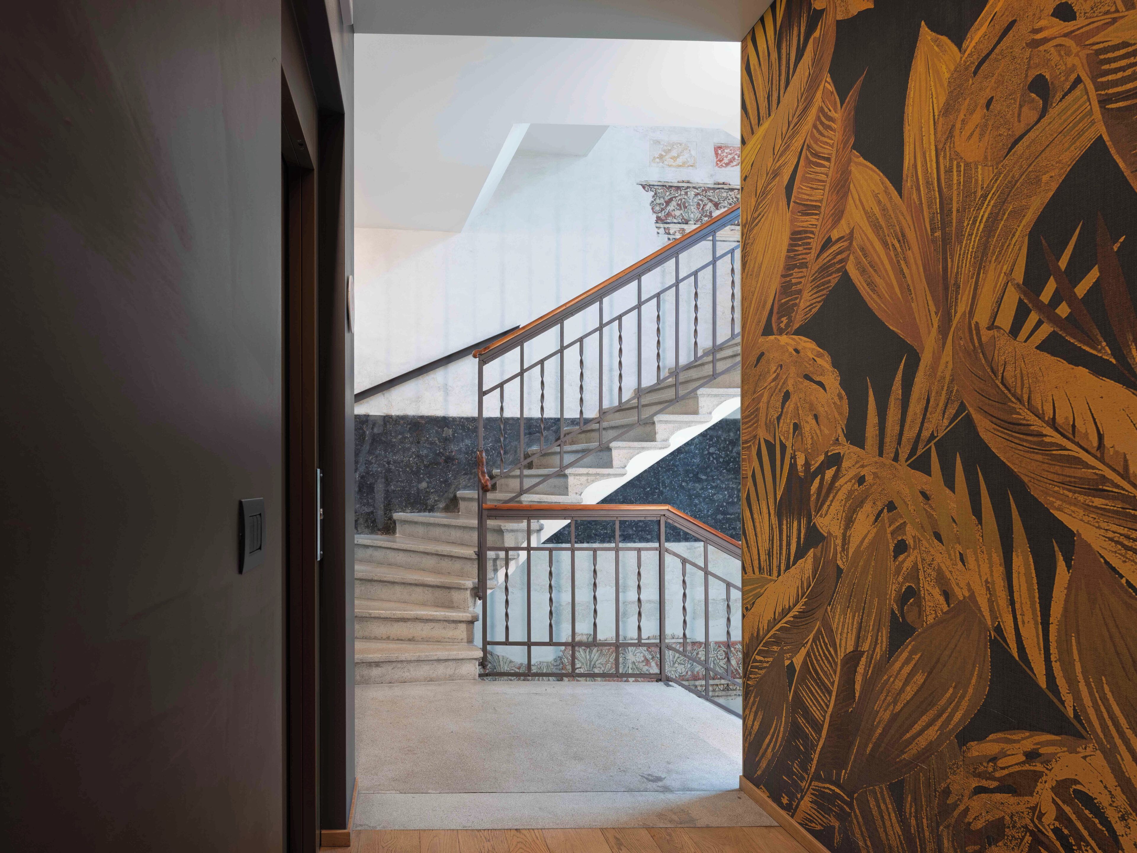 Un escalier avec une rampe métallique menant à un palier.