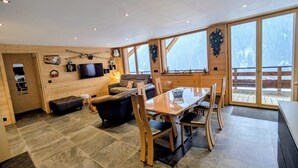 Ein modernes Interieur mit einem Holzesstisch, einer Couch und einem an der Wand befestigten Fernseher.