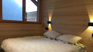Ein Schlafzimmer einer Holzhütte mit einem Bett, Kissen und einem Fenster.