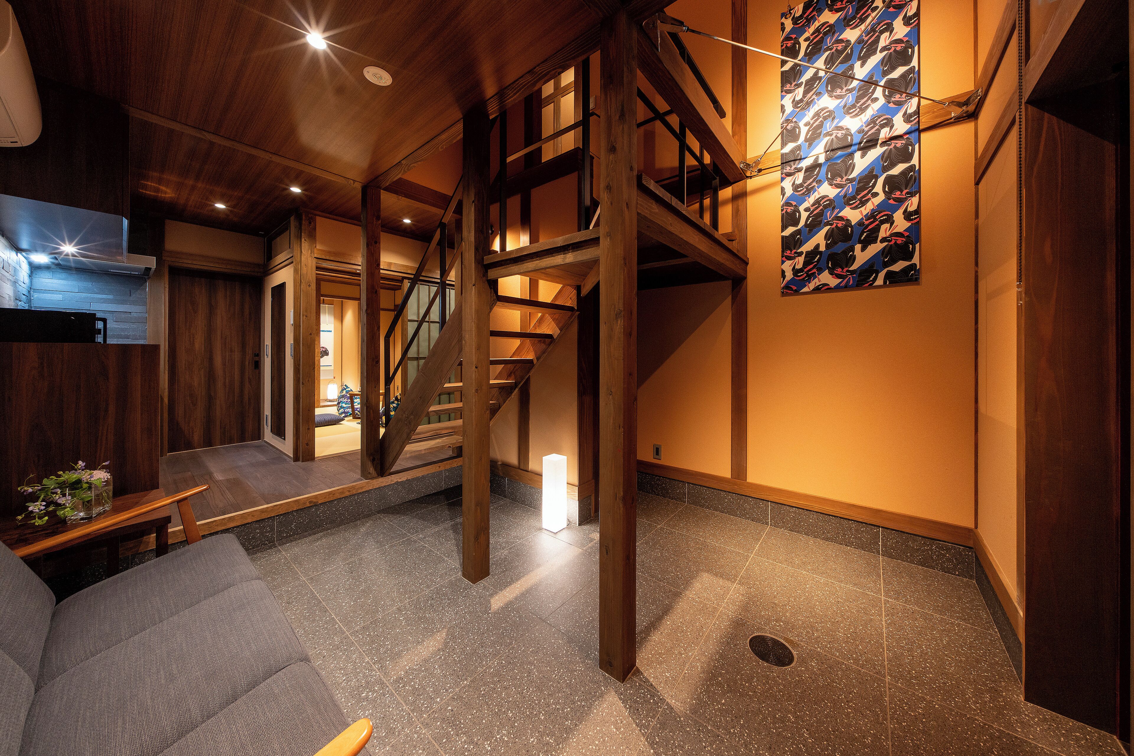 Amplio interior con escalera de madera, una zona de estar y una obra de arte colgada en la pared.