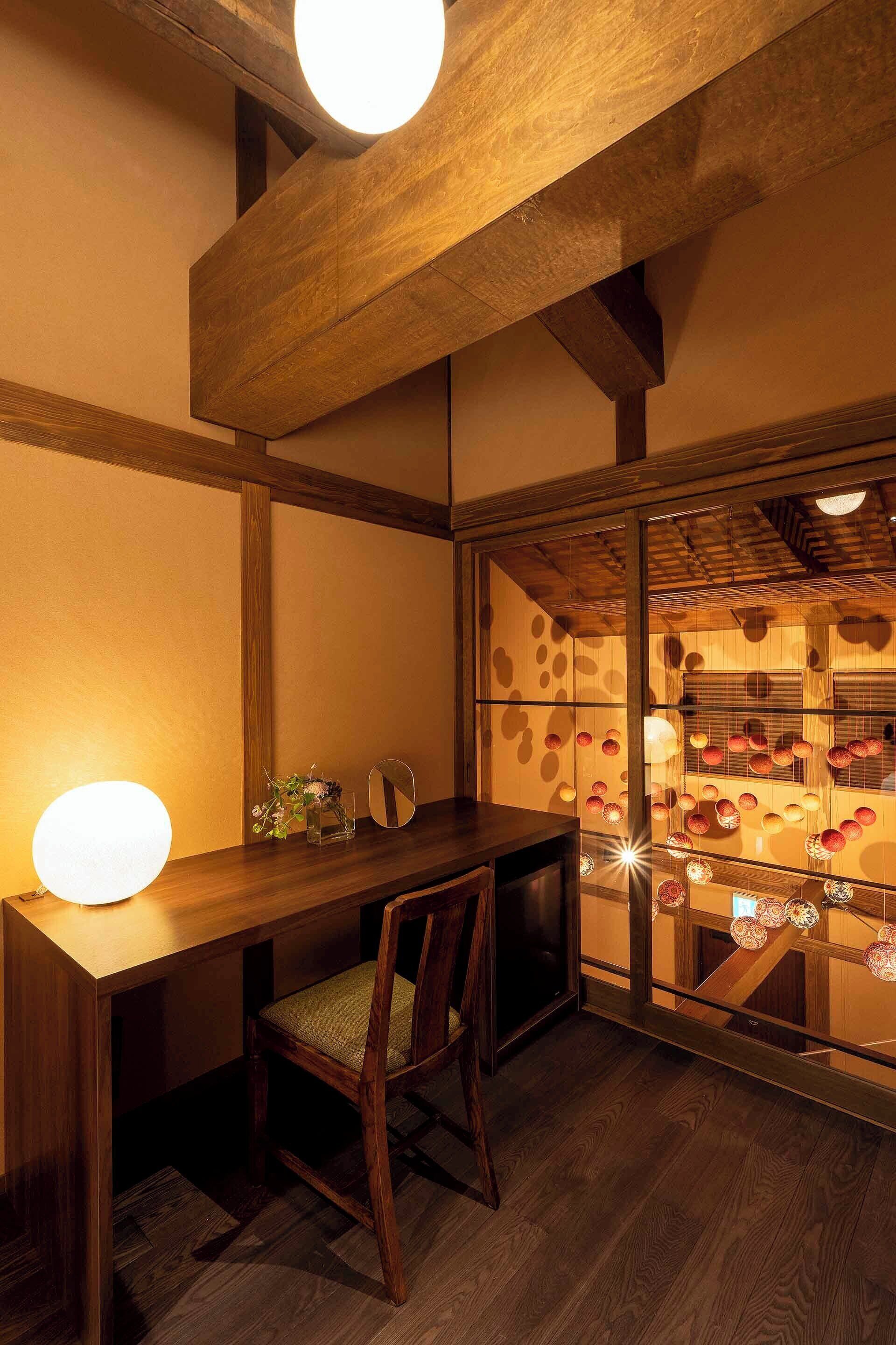 A wooden dining table with a chair, a wall-mounted mirror, and a shelf with decorative items.