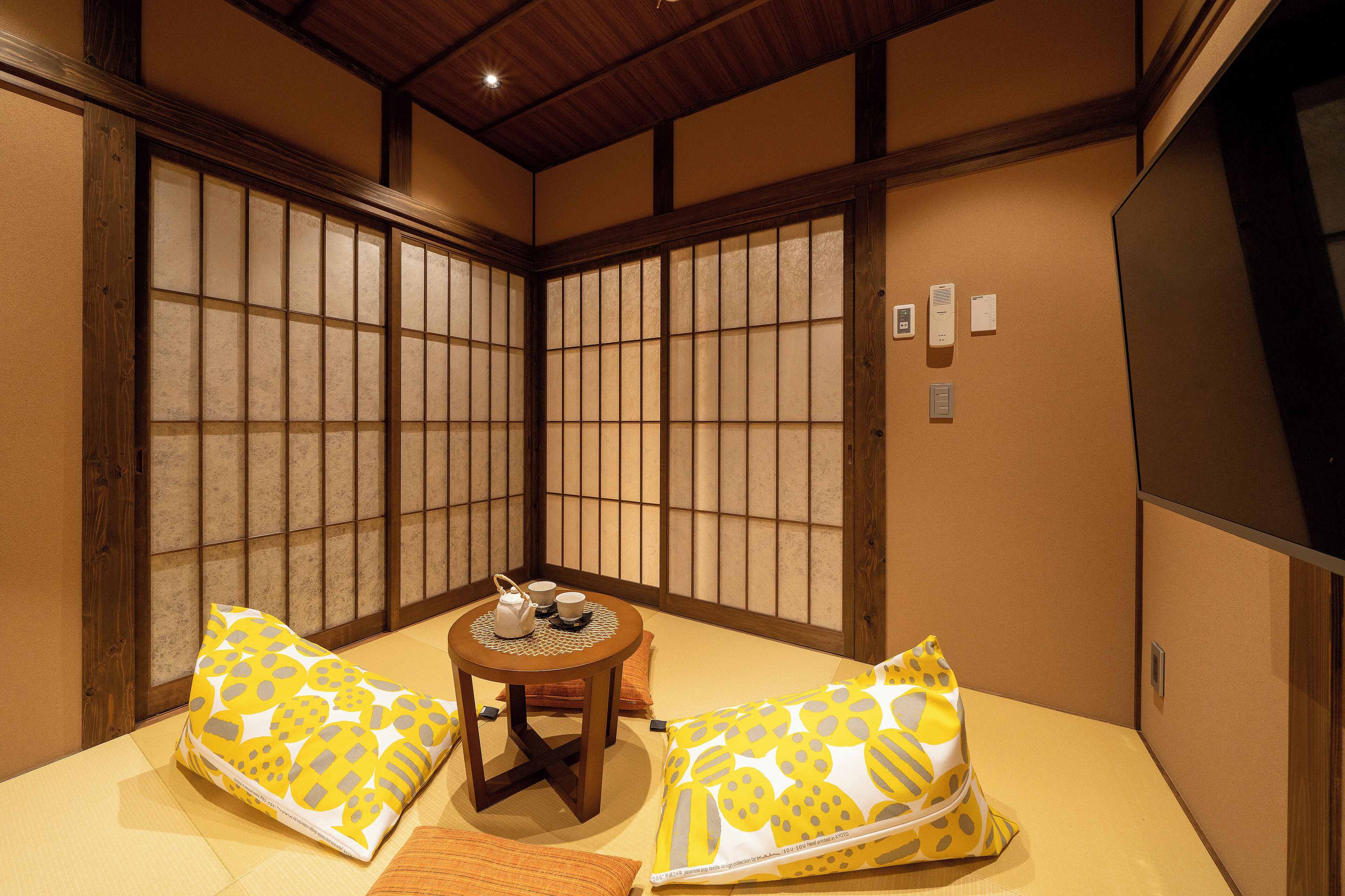 Um quarto japonês tradicional com tatames, uma mesa de madeira baixa com um conjunto de chá e biombos shoji.