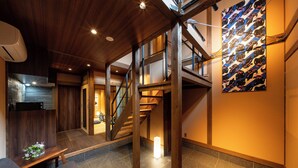 Un intérieur moderne avec un escalier, des poutres en bois et un sol carrelé.
