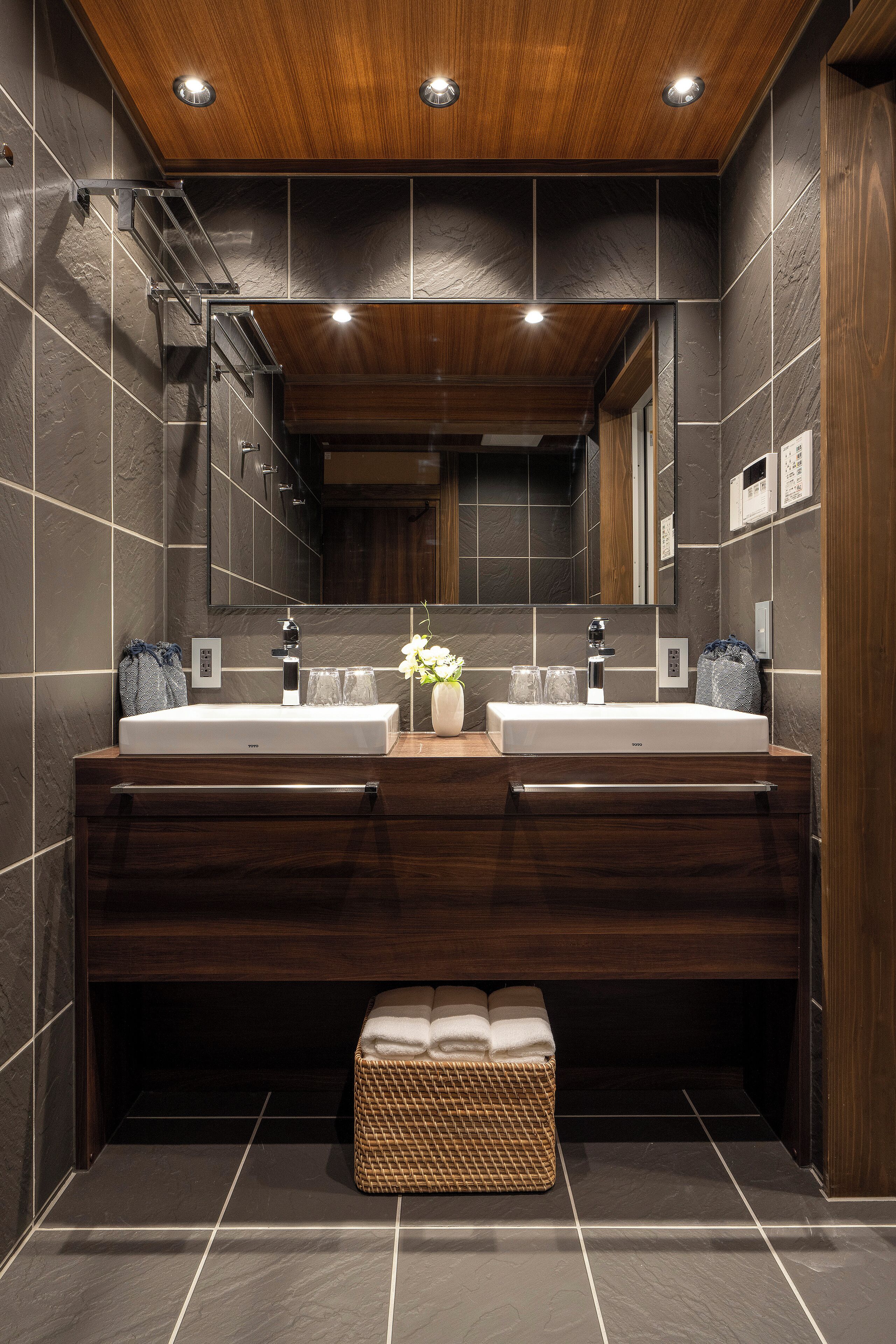 A modern bathroom with two sinks, a large mirror, and a wooden ceiling.
