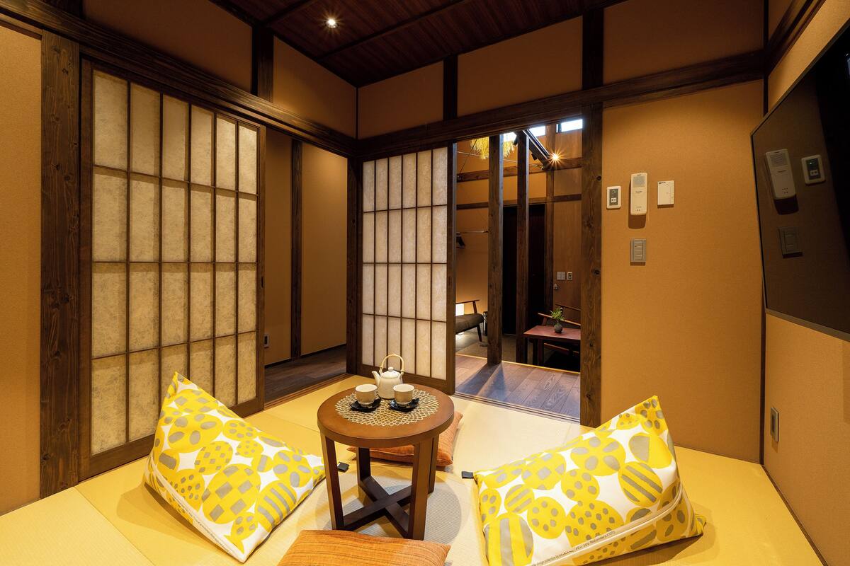 Une pièce de style japonais traditionnel, avec un sol recouvert de tatamis, une petite table en bois et un ensemble à thé, ainsi que des portes coulissantes en papier de riz (shoji).