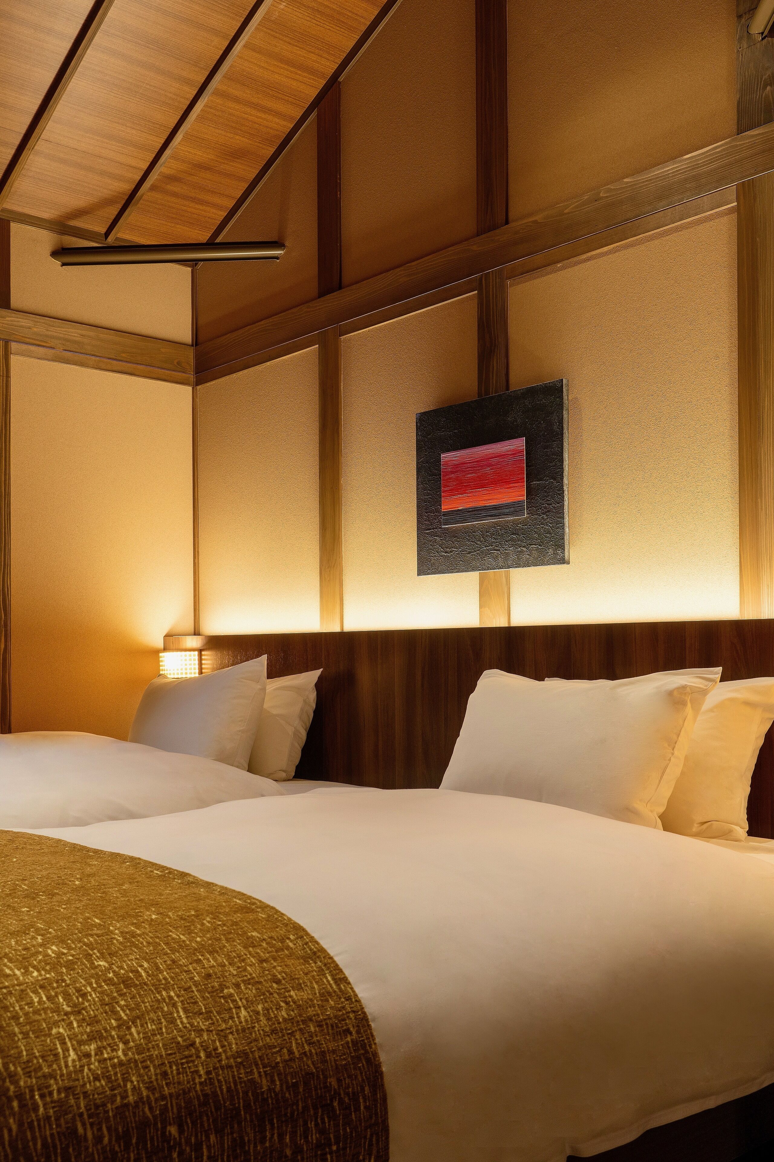 A hotel room with a large bed, wooden headboard, and a wall-mounted artwork.