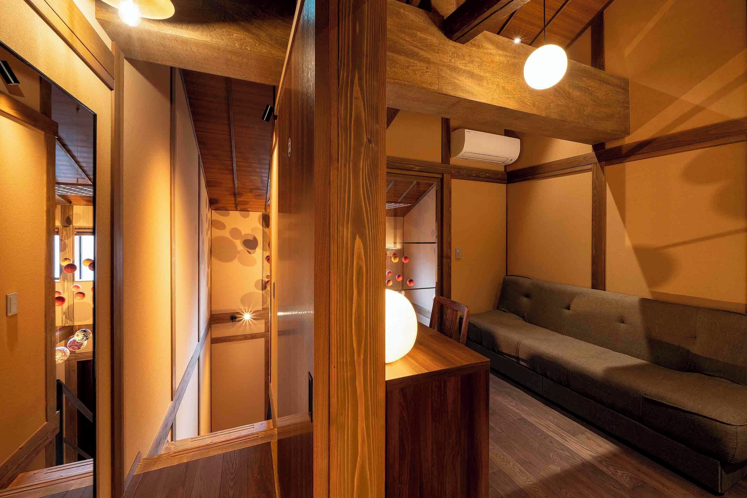 A traditional Japanese interior with a wooden ceiling, a sofa, and a table with a light fixture.