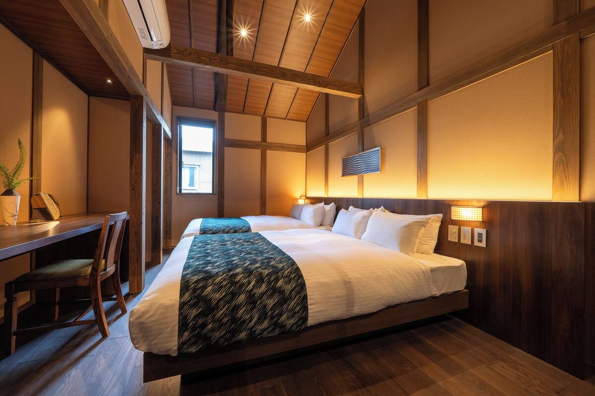 Une chambre d’hôtel avec un grand lit, un bureau et une chaise. Il y a une fenêtre et un téléviseur fixé au mur.