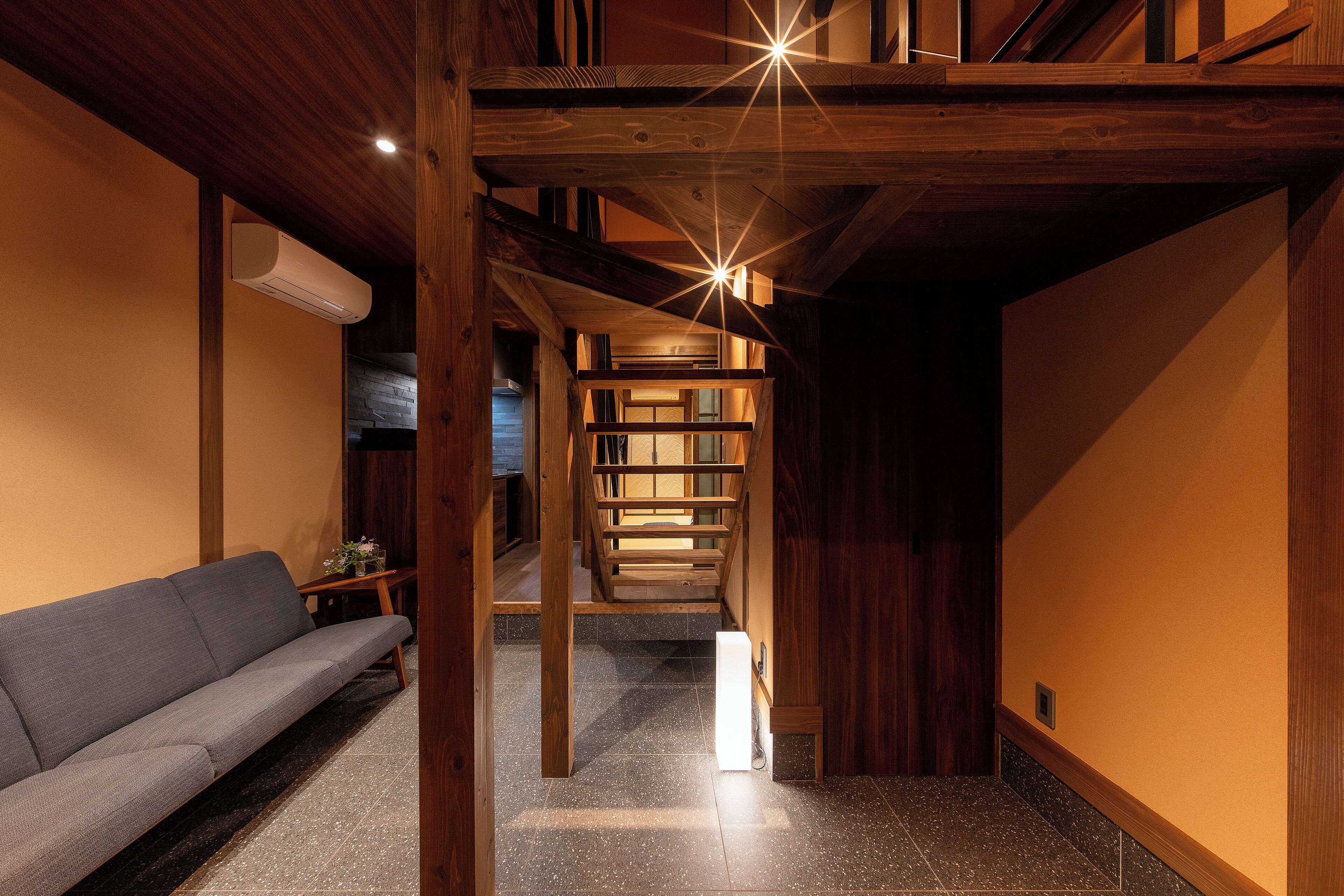 A wooden interior with a sofa, a staircase, and a ceiling light fixture.