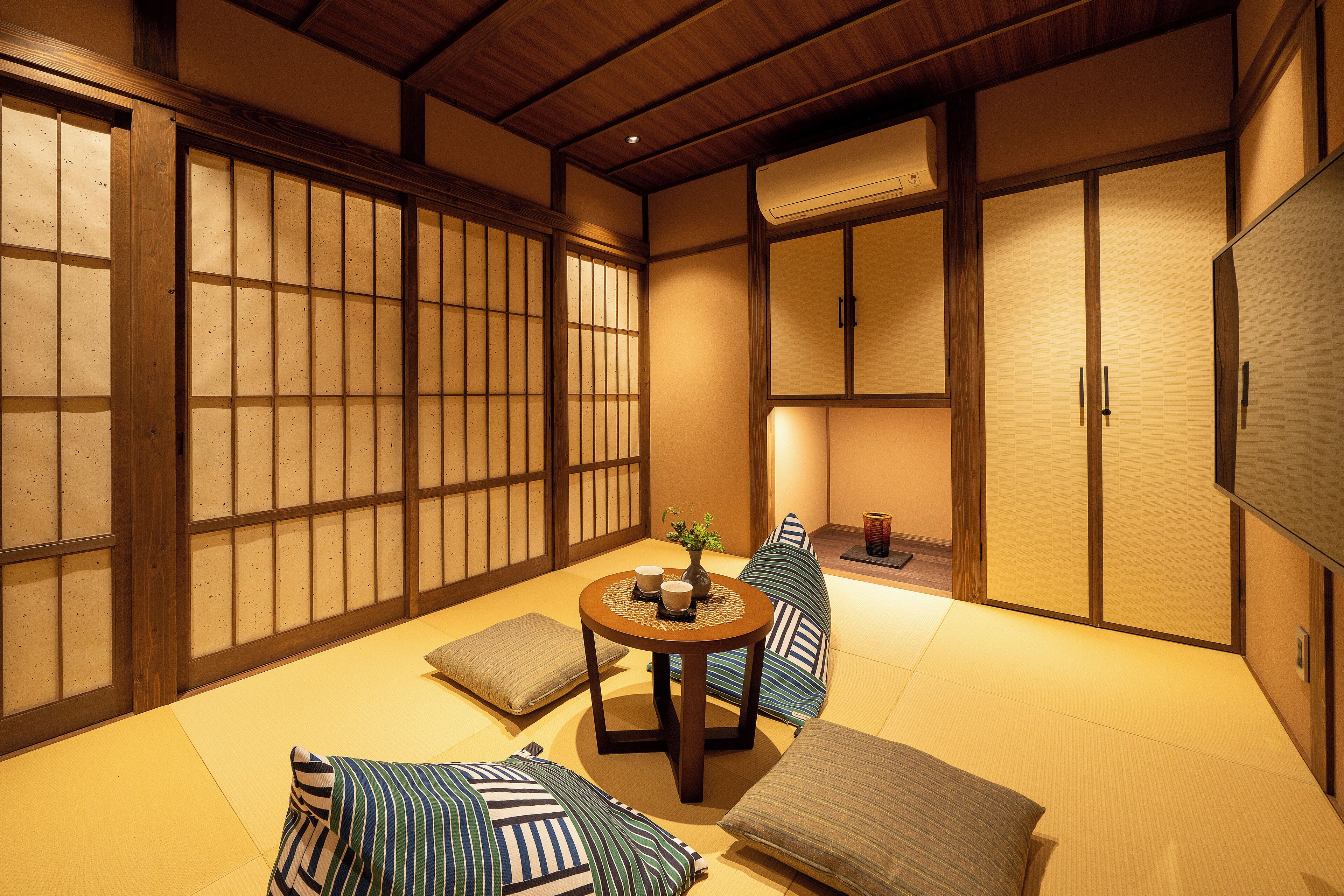 A traditional Japanese room with tatami flooring, shoji screens, and a low table with cushions.