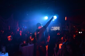 A crowded indoor event with a DJ booth and a neon sign in the background. - HOME Hotel (Ho Chi Minh City)