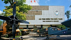 A war memorial with a large sign and several vintage aircraft on display. - HOME Hotel (Ho Chi Minh City)