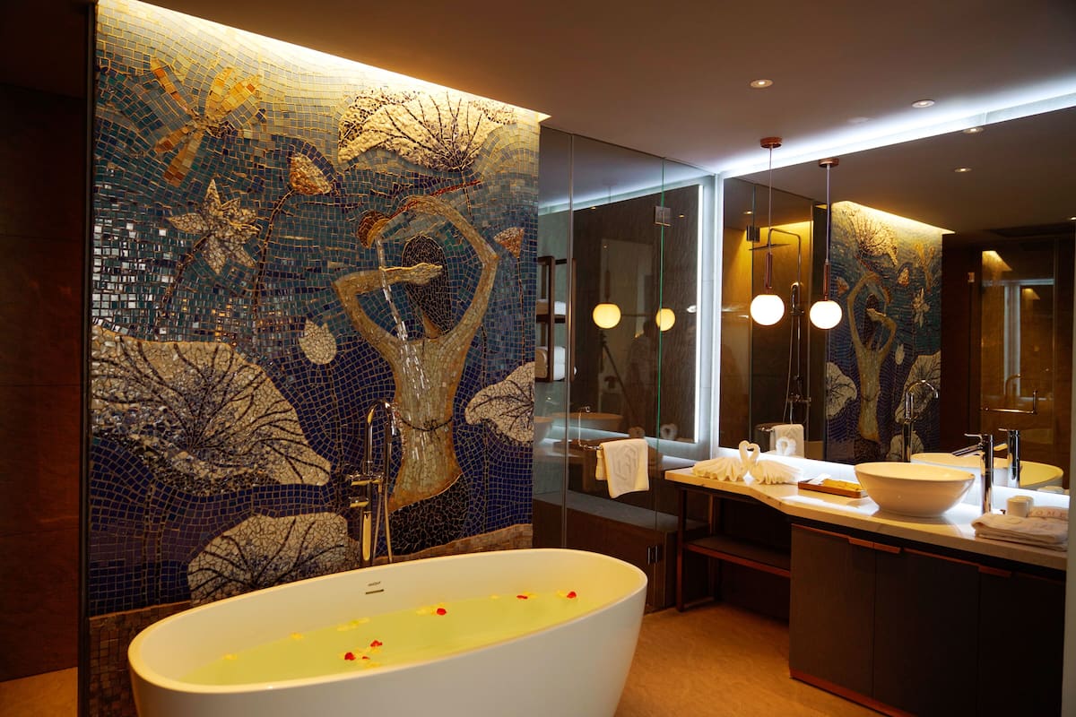 Een moderne badkamer met een groot bad, een douche met glazen wanden en een mozaïekwand.