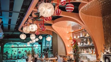 A bar area with a curved counter, hanging decorations, and shelves with bottles.