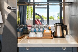 A kitchenette with a coffee maker, water bottles, and a 'Welcome Home' sign. - HOME Hotel (Ho Chi Minh City)