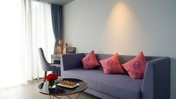 Una sala de estar moderna con un sofá gris, dos almohadas rojas, una mesa de centro de cristal y una silla.