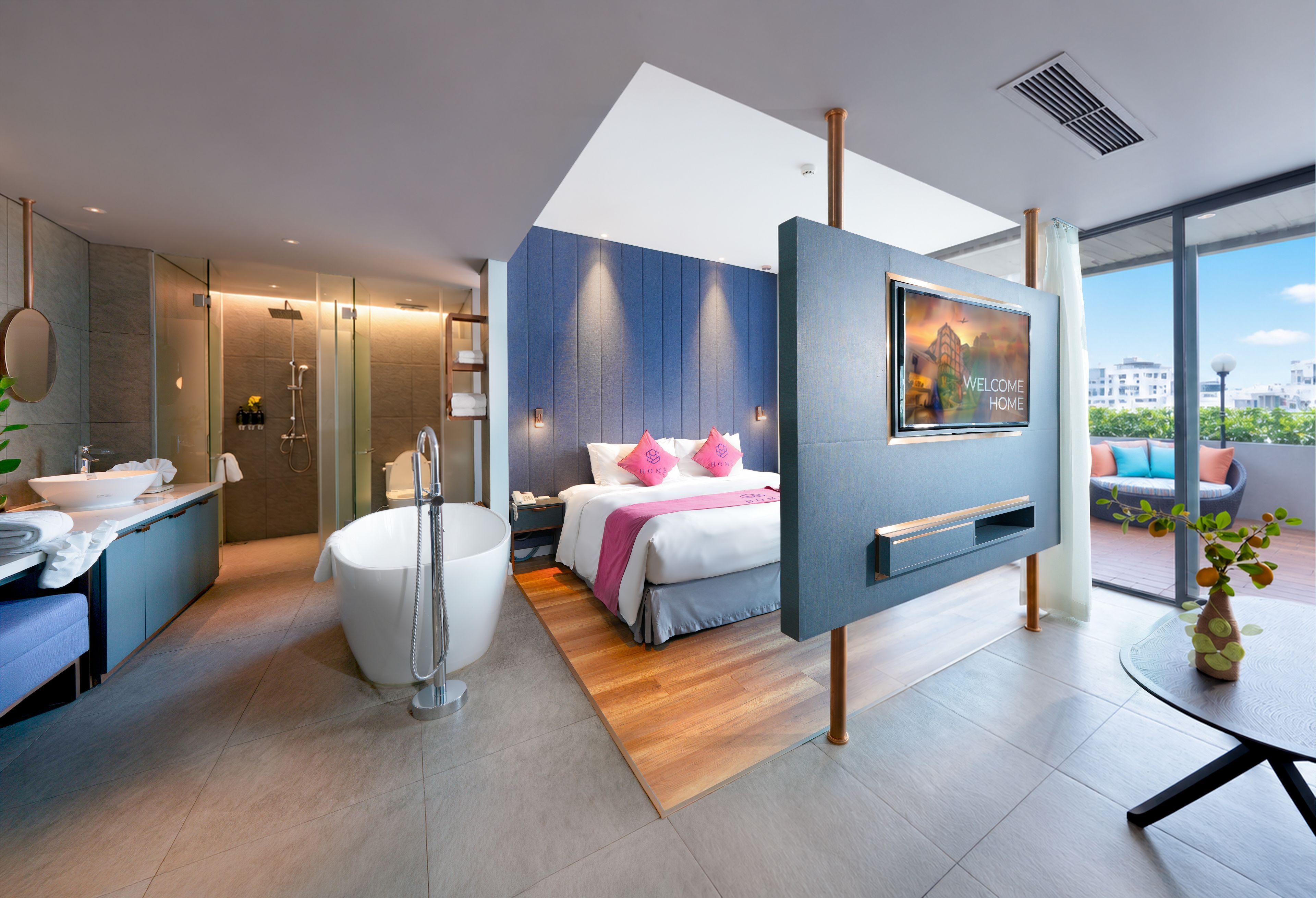 Una habitación de hotel moderna con una cama grande, una bañera, un tocador con lavabo y un televisor montado en la pared.