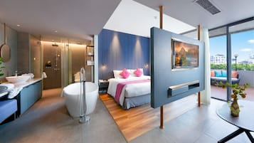 Una habitación de hotel moderna con una cama grande, una bañera, un tocador con lavabo y un televisor montado en la pared.