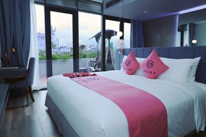 A hotel room with a large bed, a desk, and a view of the city through large windows. - HOME Hotel (Ho Chi Minh City)