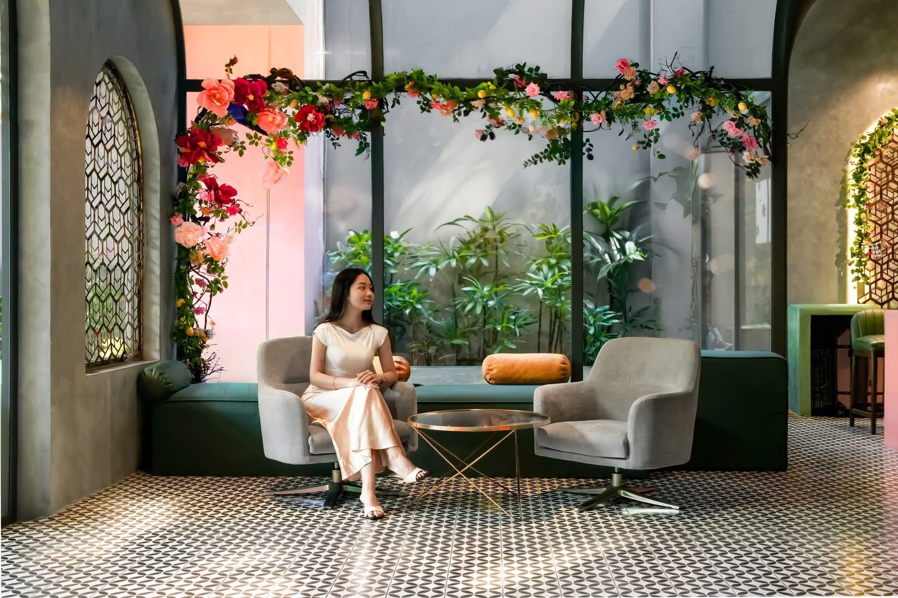 Un interior moderno con una zona de estar, un arreglo floral decorativo y vistas al verdor a través de amplios ventanales.