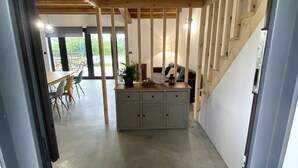 A modern interior with exposed wooden beams, a grey cabinet, and a staircase leading to another level.