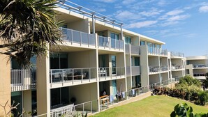 Un hôtel à plusieurs étages doté de balcons, d’un espace extérieur aménagé pour s’asseoir et d’une pelouse bien entretenue.