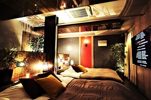 Una habitación de hotel moderna con una cama grande, una pared de acento roja y un televisor montado en la pared.