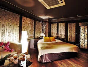 Un dormitorio amplio con una cama grande, una mesita de noche con objetos decorativos y vistas por la ventana.