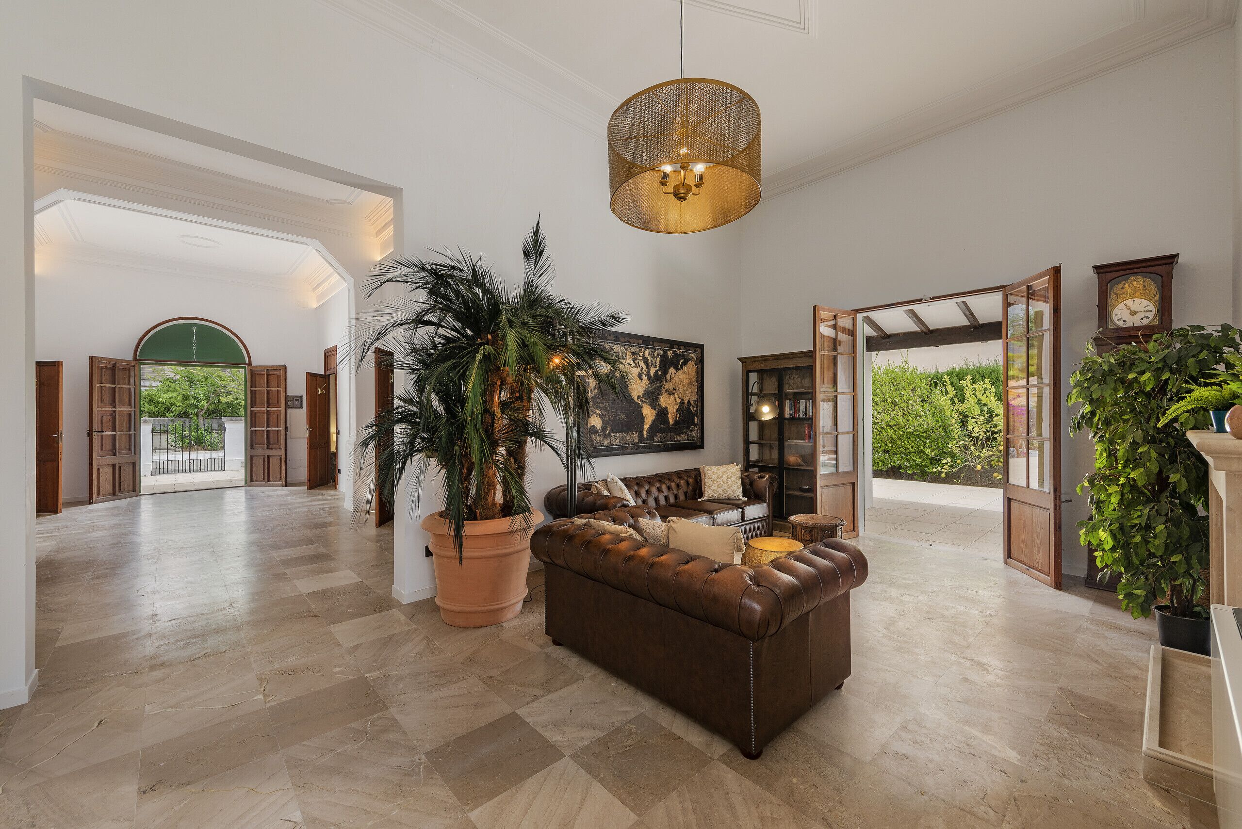 A spacious living area with a large sofa, a potted plant, and a hanging light fixture.