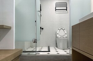 A modern bathroom with a glass shower enclosure, a toilet with a white seat, and a wooden vanity. - Little Inn (Kaohsiung)