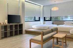 A modern bedroom with a TV, a wooden bench, and a bed with white bedding. - Little Inn (Kaohsiung)