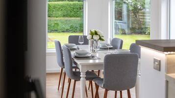 A dining area with a table set for six, large windows, and a view of a garden.