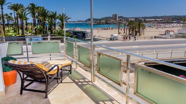 Een balkon met rieten meubilair en uitzicht op het strand.