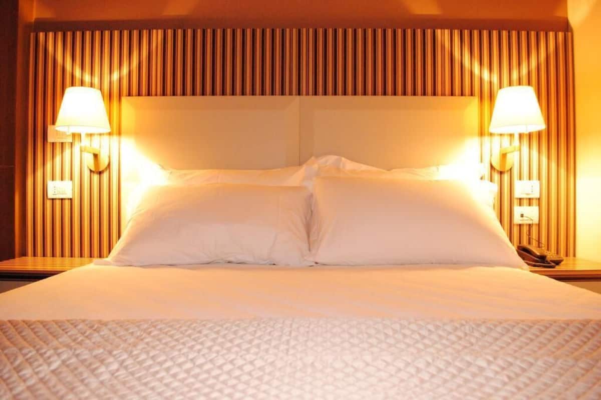 Ein Hotelzimmer mit einem großen Bett, zwei Nachttischlampen und einem Telefon auf dem Nachttisch.