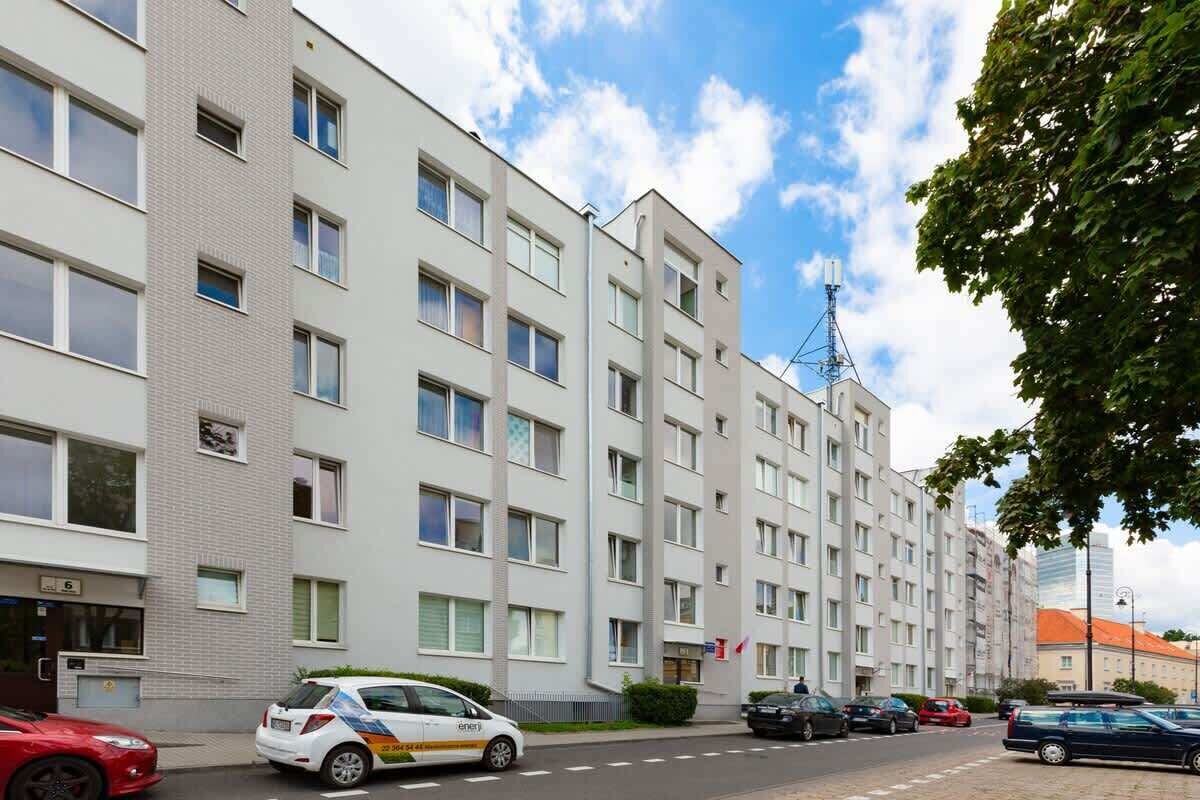 Un edificio residencial de varios pisos con fachada uniforme, varias ventanas y una bandera visible.