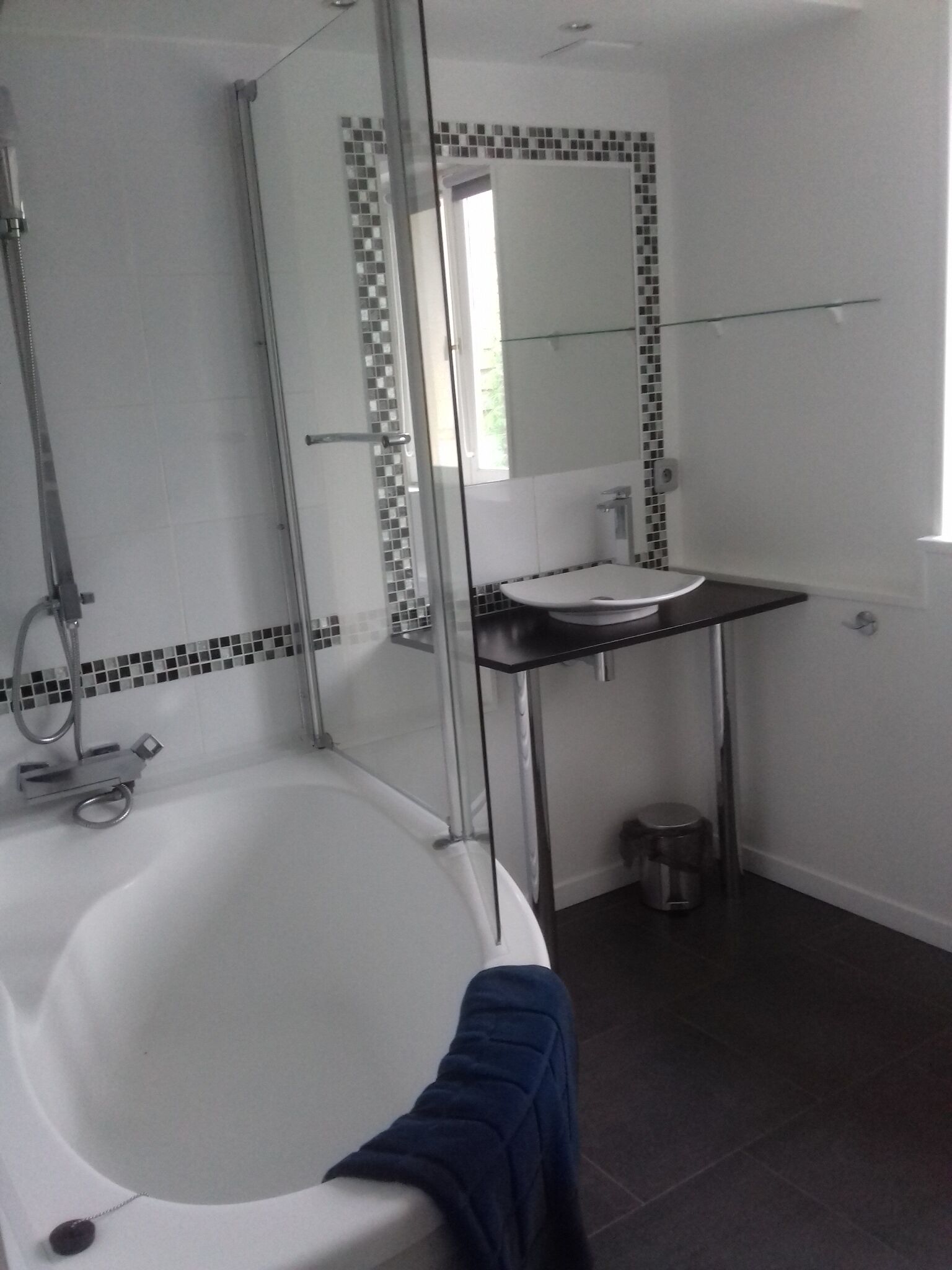 Une salle de bain avec une douche à parois de verre, une baignoire blanche, un lavabo et un miroir.