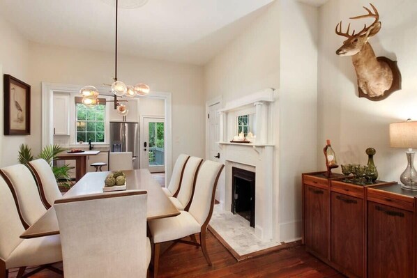 Un coin repas avec une table et des chaises en bois, une cheminée et une tête de cerf accrochée au mur.