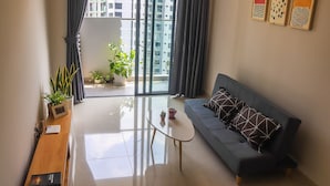 A modern living room with a sofa, coffee table, and potted plants. - Spacious and Modern Service Apartment in Hochiminh (Ho Chi Minh City)