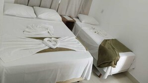 A hotel room with two beds, each with a neatly folded towel and a brown nightstand. - Pousada Recanto das Vertentes (Capitólio)