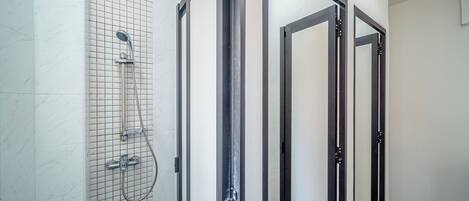 A bathroom with a tiled shower area, a glass door, and a mirror.